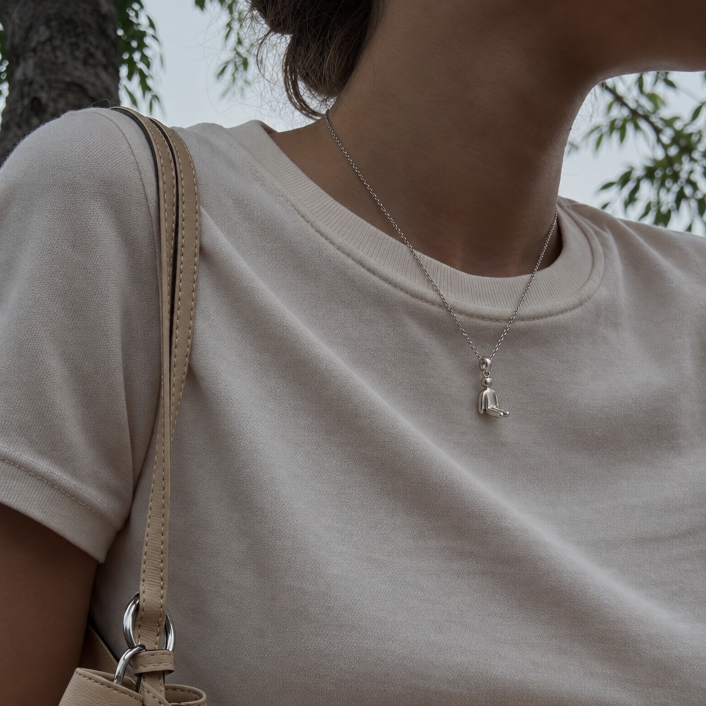 A model wearing the Stillness Figure Pendant on a fine silver chain
